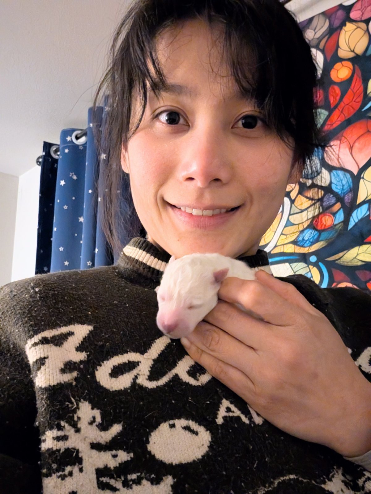Me holding a newborn puppy against my chin, smiling